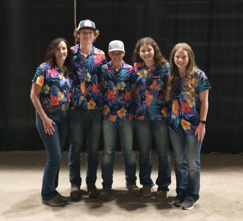 Five people in matching floral shirts smile for the camera