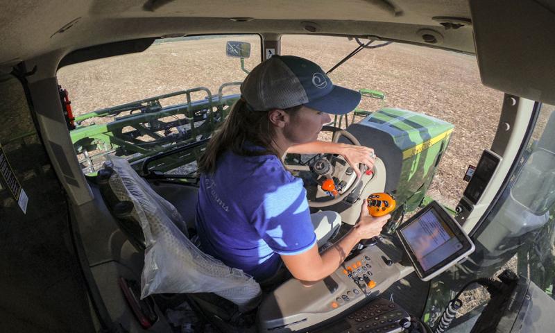 Female producer piloting a crop sprayer through a field.
