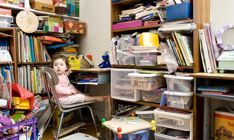 Toddler sitting in a cluttered room.