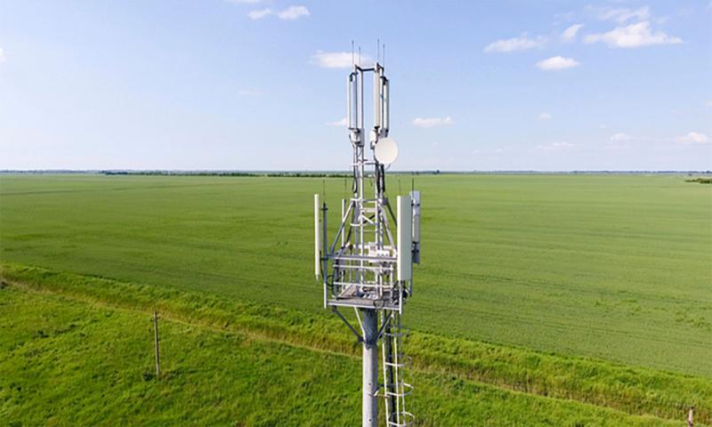 Rural cellular tower on the edge of a sprawling agricultural field.