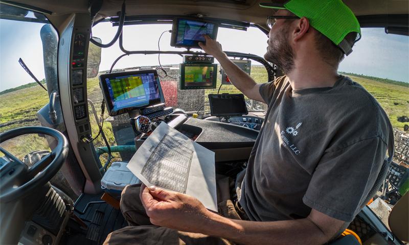 Producer analyzing data on a series of screens inside a tractor equipped for precision agriculture.