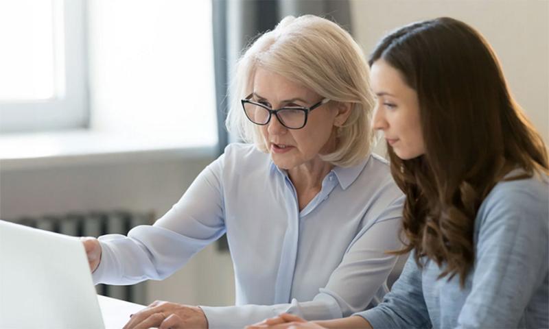 Mother and daughter reviewing information on a laptop computer screen.