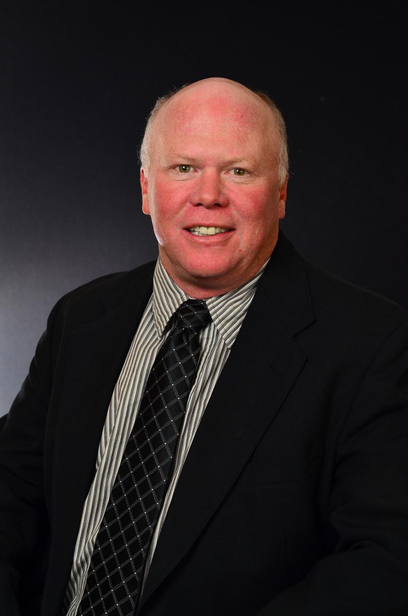 A man in a suit and tie smiles for a portrait
