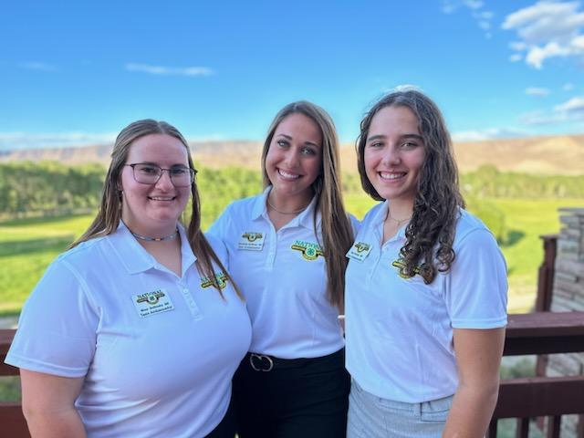 Three girls wearing shirts with National Shooting Sports insignia smile for the camera