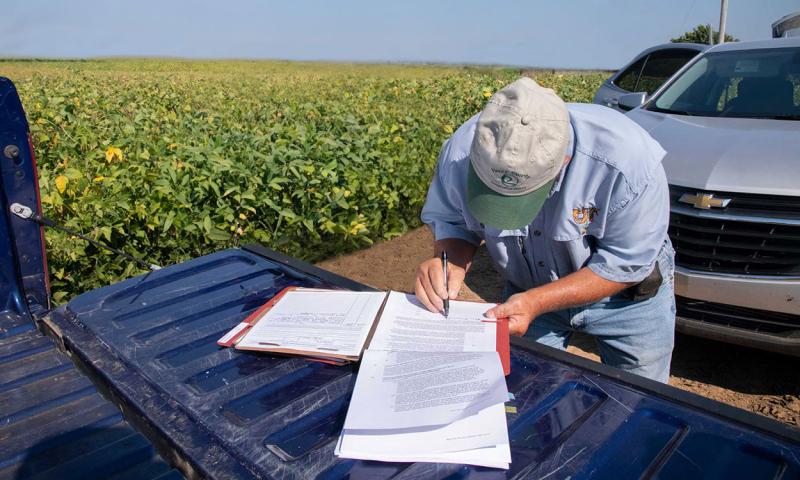 Farmer signing a lease on the tailgate of a pickup.