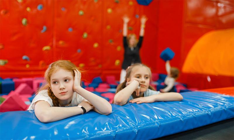 Two visibly tired children in an indoor climbing and fitness facility.
