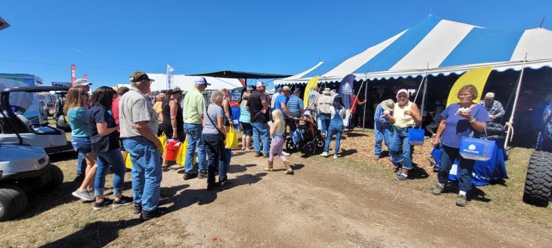 People line up outside a blue-and-white-striped tent