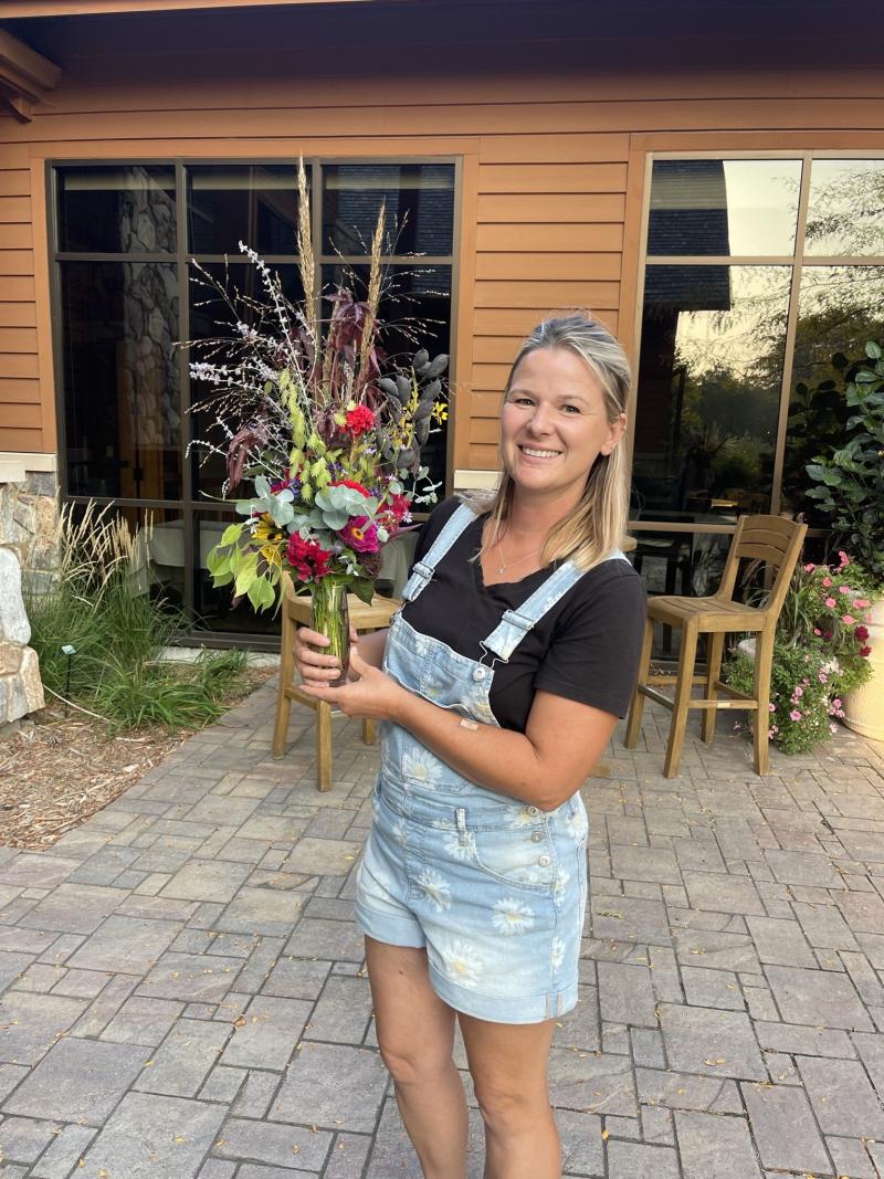 A woman holds a bouquet of flowers in a glass vase