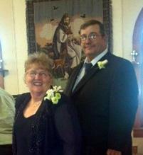 A man and a woman wearing floral boutonnieres smile for the camera