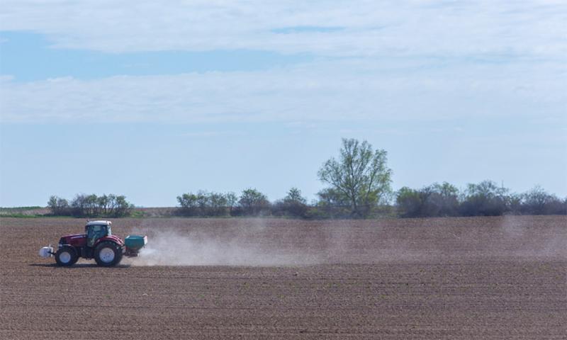 Tractor applying residual herbicide to a bare field.