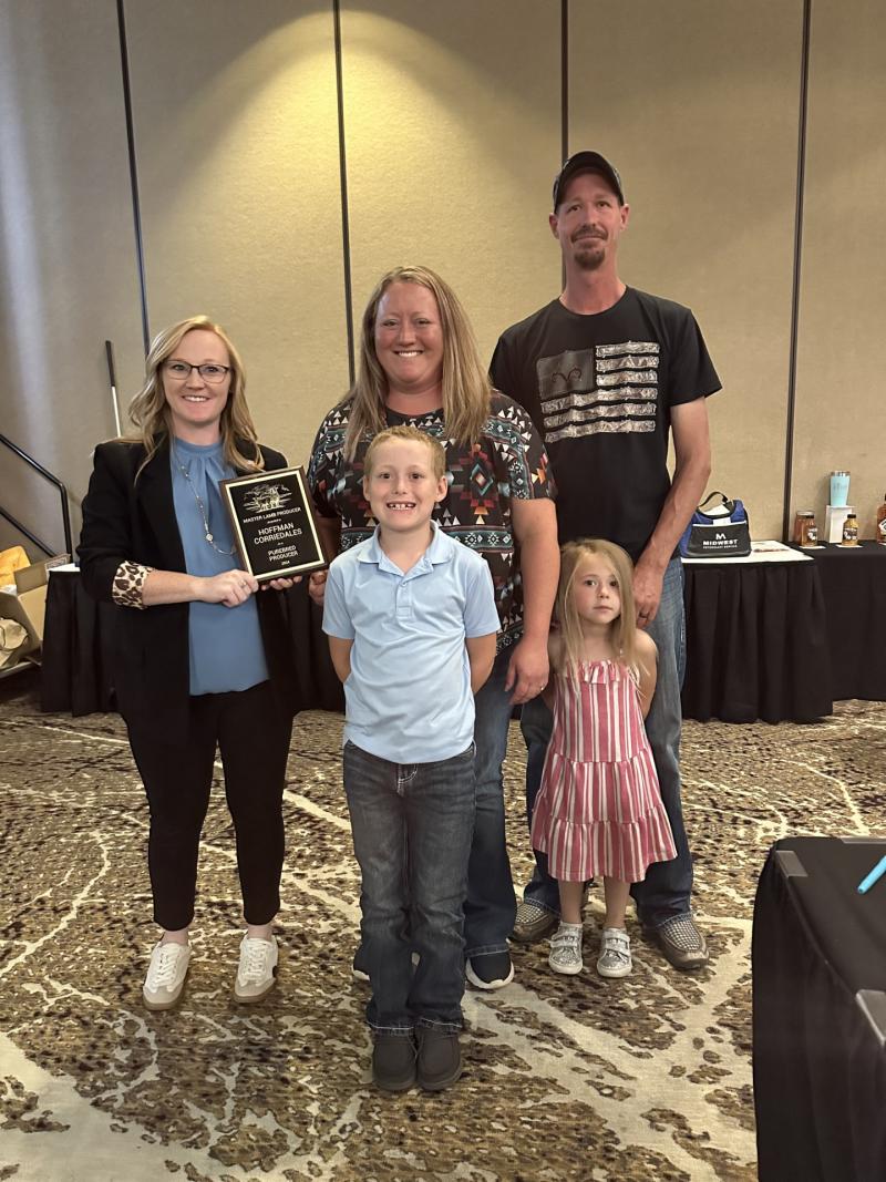 A family of four is presented a plaque by a woman in professional dress