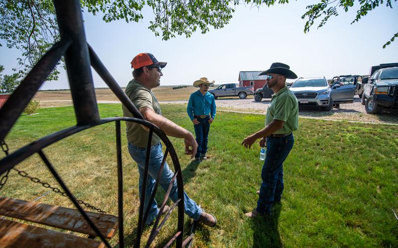 A group of male ranchers gathered in a farmyard.