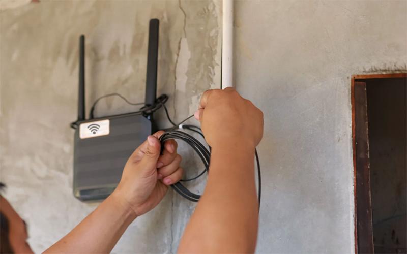 Technician installing a wireless internet router on an exterior structure.