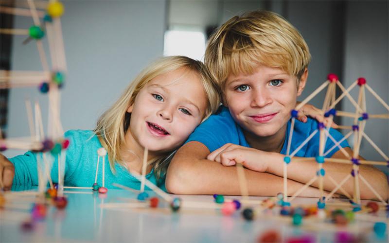 A young girl and boy playing with a STEM geometric building kit.