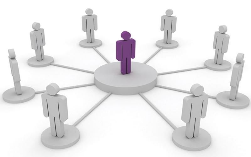 A single wood figure surrounding by a circle of other wood figures, symbolizing democratic leadership style.