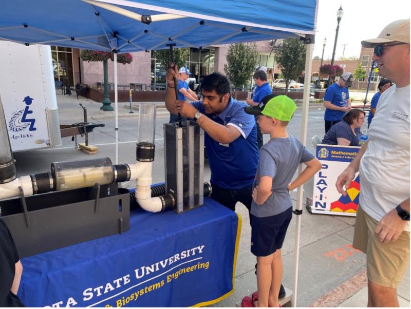 A man uses a tile drainage model while a boy watches