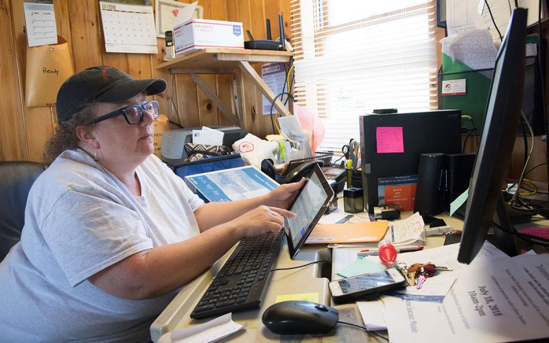 Producer in a farm office using a tablet and a computer.