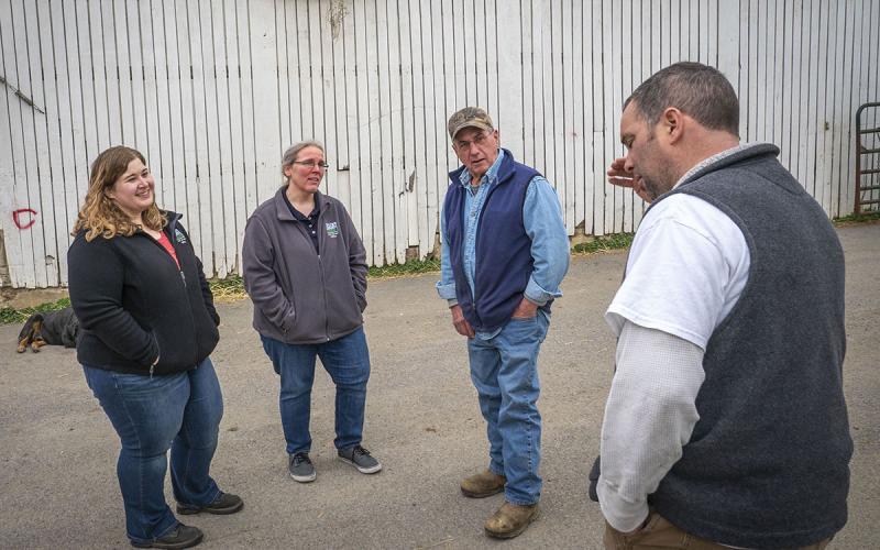 Ranchers meeting with USDA agents in a farmyard.