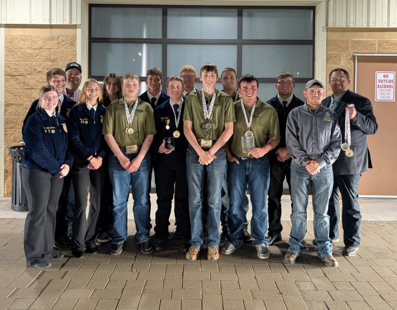 A group of youth smile for the camera wearing medals around their necks