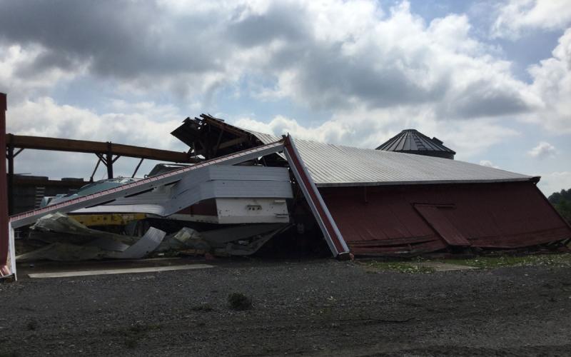 Barn and farmyard with severe structural damage from a windstorm.