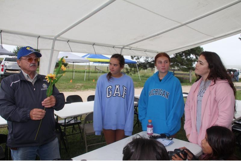 A man shows a flowering plant to three ladies
