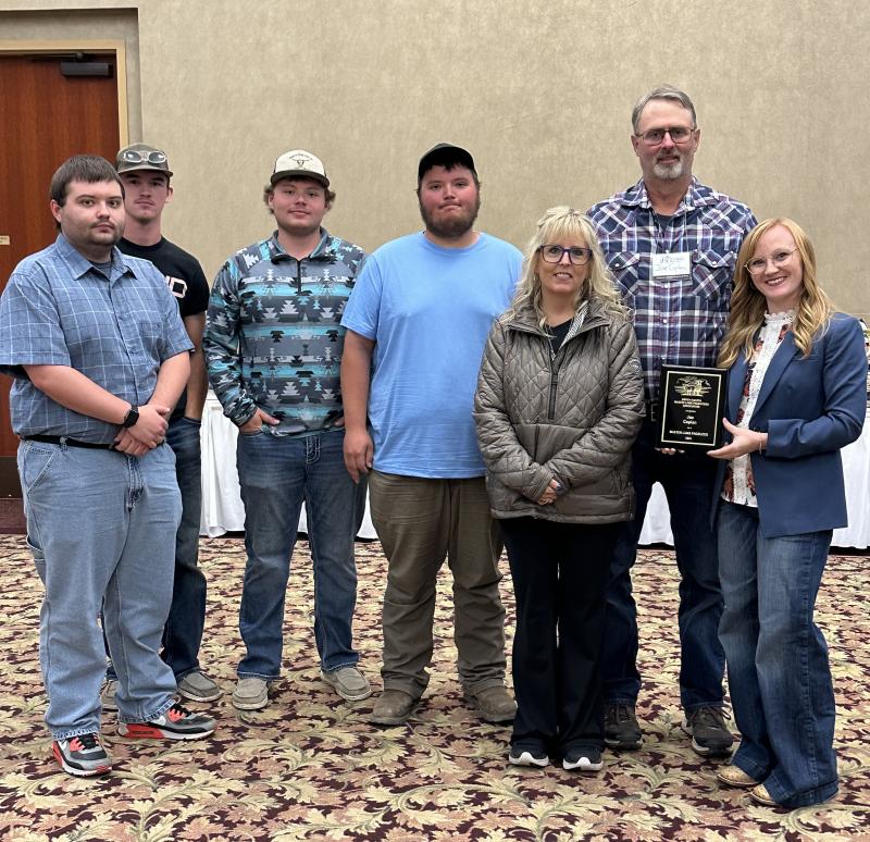 A family smiles with an award plaque