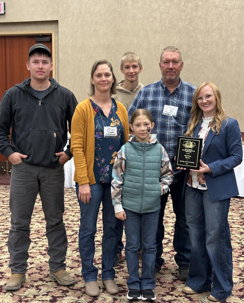 A family smiles with an award plaque