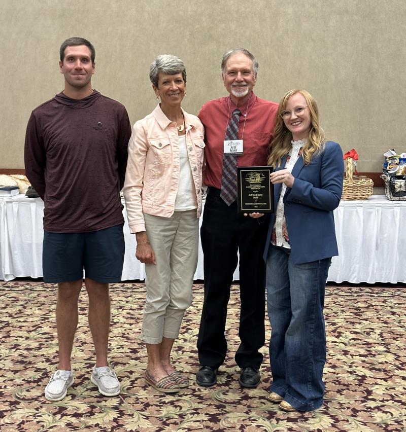A family smiles with an award plaque