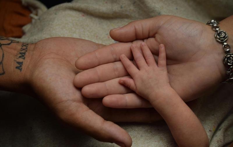 Parents holding a baby’s hand.