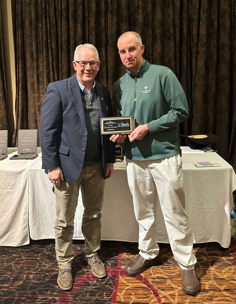 Two men hold a plaque for honorary Master Pork Producer