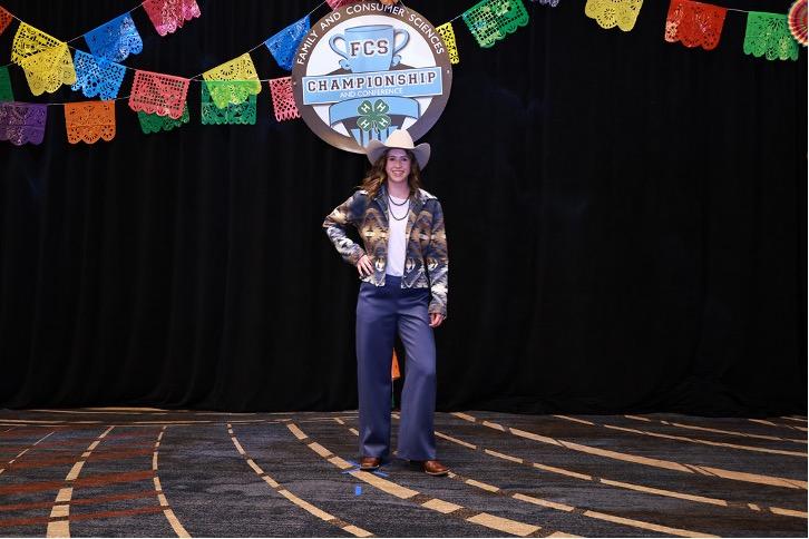 A girl in a cowboy hat and western outfit poses