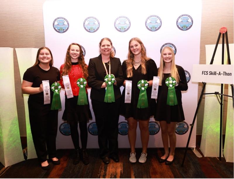 A group of people holds ribbons in front of an FCS backdrop