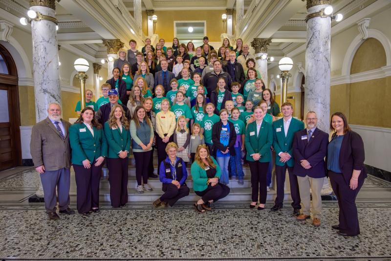 A large group of people stands on the Capitol steps and smiles for the camera