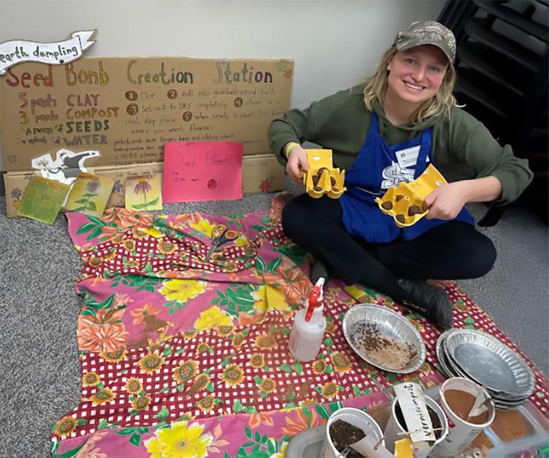 A young master gardener setting up a “make your own seed bomb” station at a seed swap.