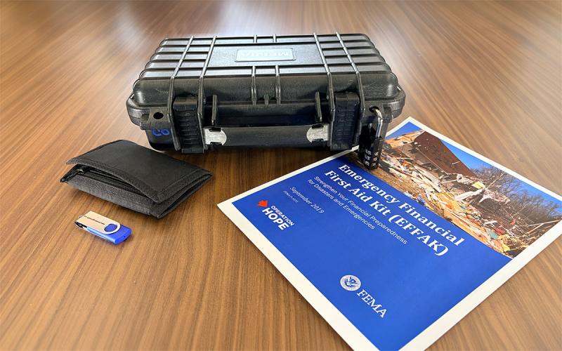USB drive, emergency wallet, locked flight case, and emergency checklist arranged on a table.