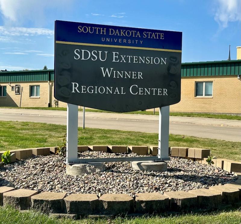 sign with the words South Dakota State University SDSU Extension Winner Regional Center in a landscaped area with bricks and rocks