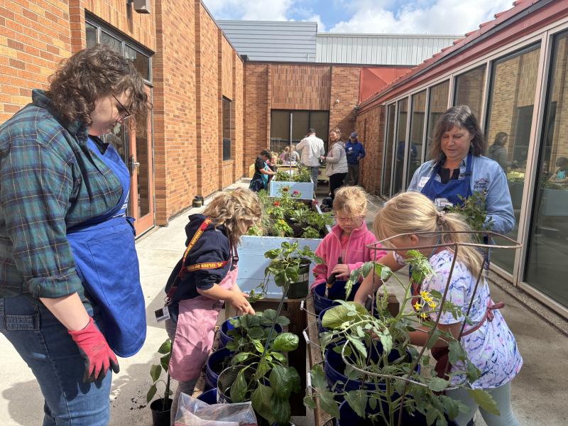 Youth and two adult helpers work with plants in box planters