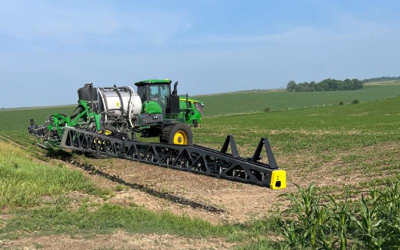 Herbicide sprayer on the edge of an emerging soybean field.