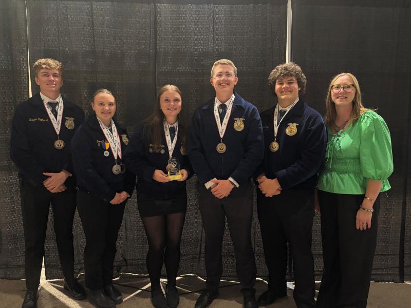 Six people smile for the camera wearing third-place medals