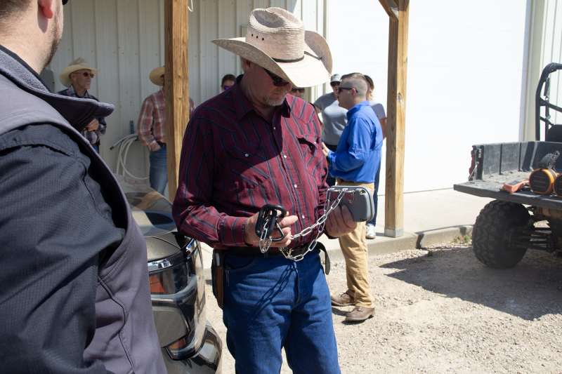 A man in a cowboy hat holds a collar with box on one side