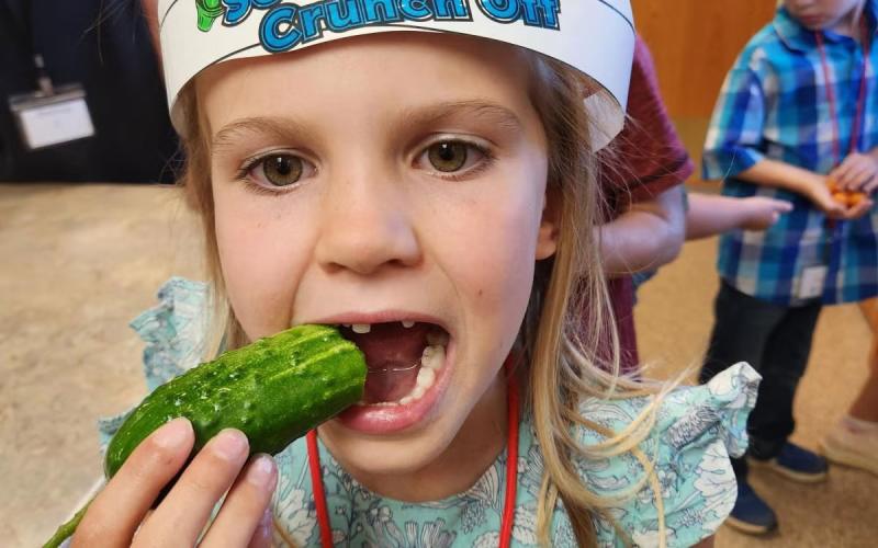 Young girl wearing a South Dakota Crunch Off crown and biting into a cucumber