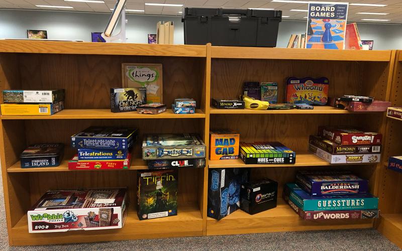 Library shelf with various board games that can be checked out.