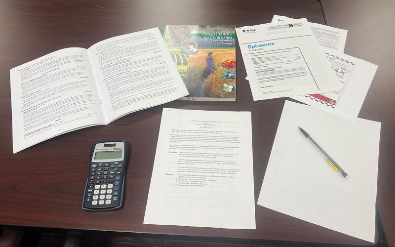Pesticide applicator exam materials arranged on a desktop.