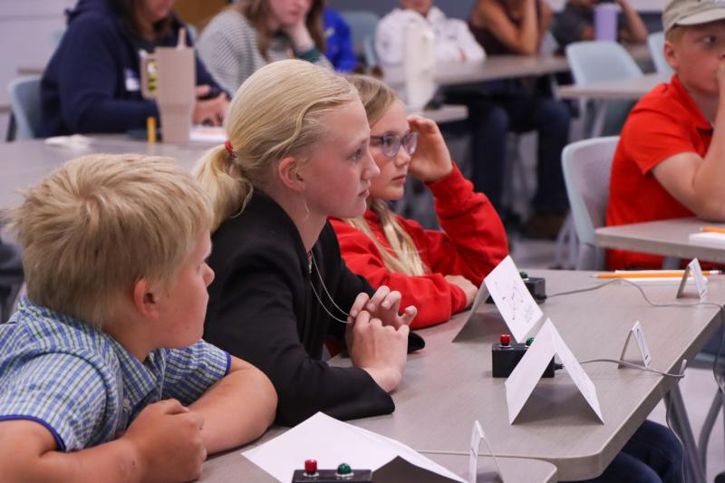 Youth sit at a table with a buzzer in front of their hands