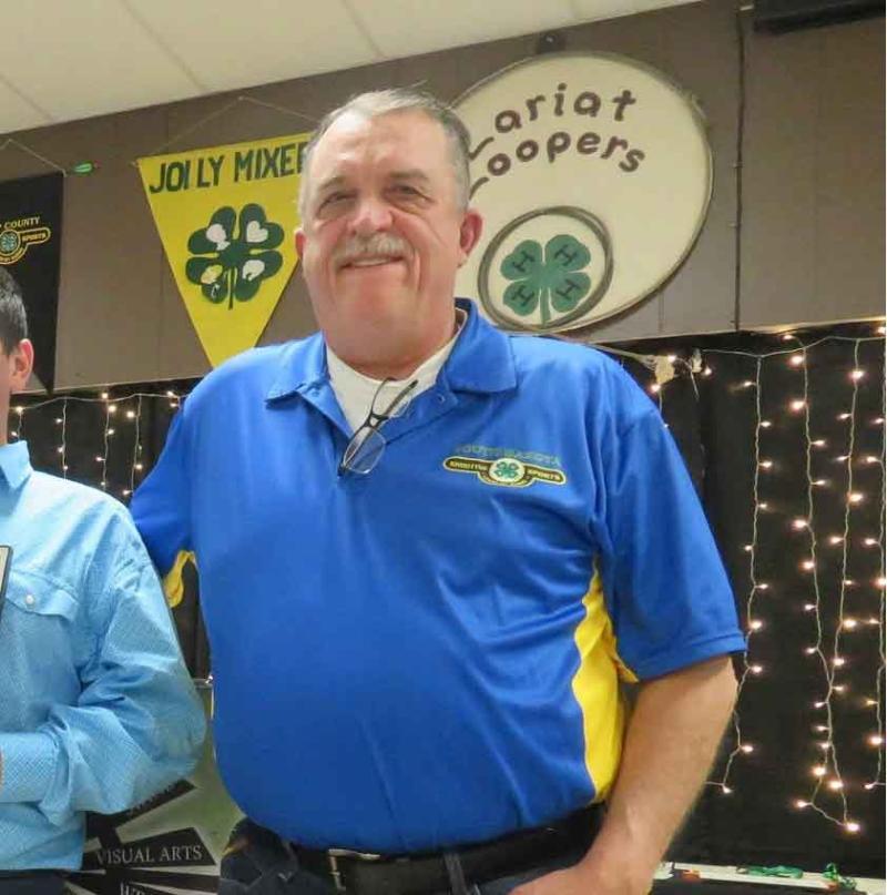 An older man wearing a blue polo shirt smiles for the camera