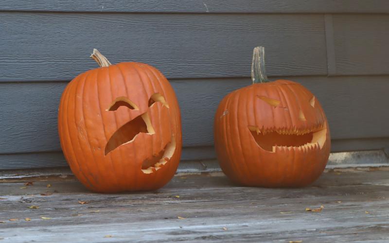 Two, well-preserved carved pumpkins sitting on a front porch.