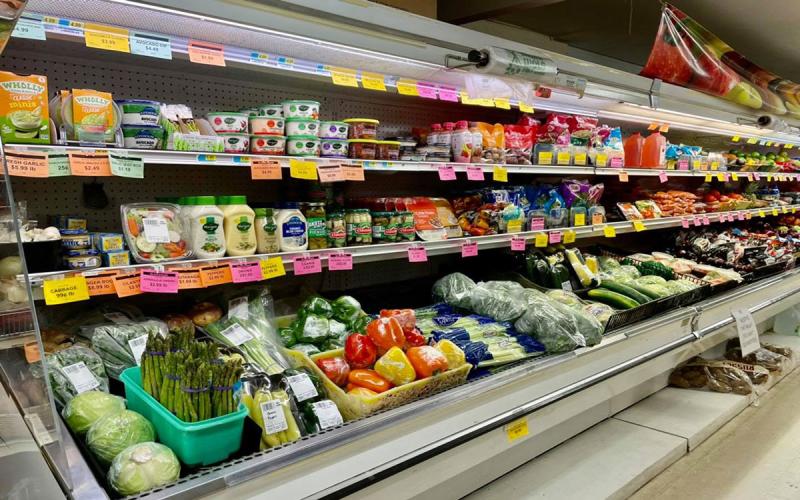 Variety of fresh fruits and vegetables on display in the produce section of a small-town grocery store.