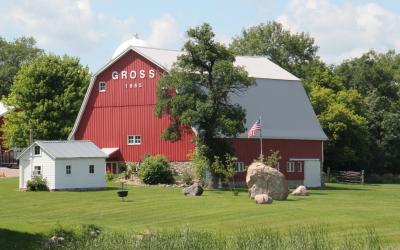 red barn with a white shed in front of it and trees in the background