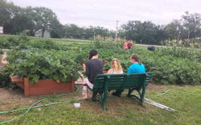 kids sitting on a bench in front of a community garden