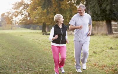 an elderly man and woman walking on green grass